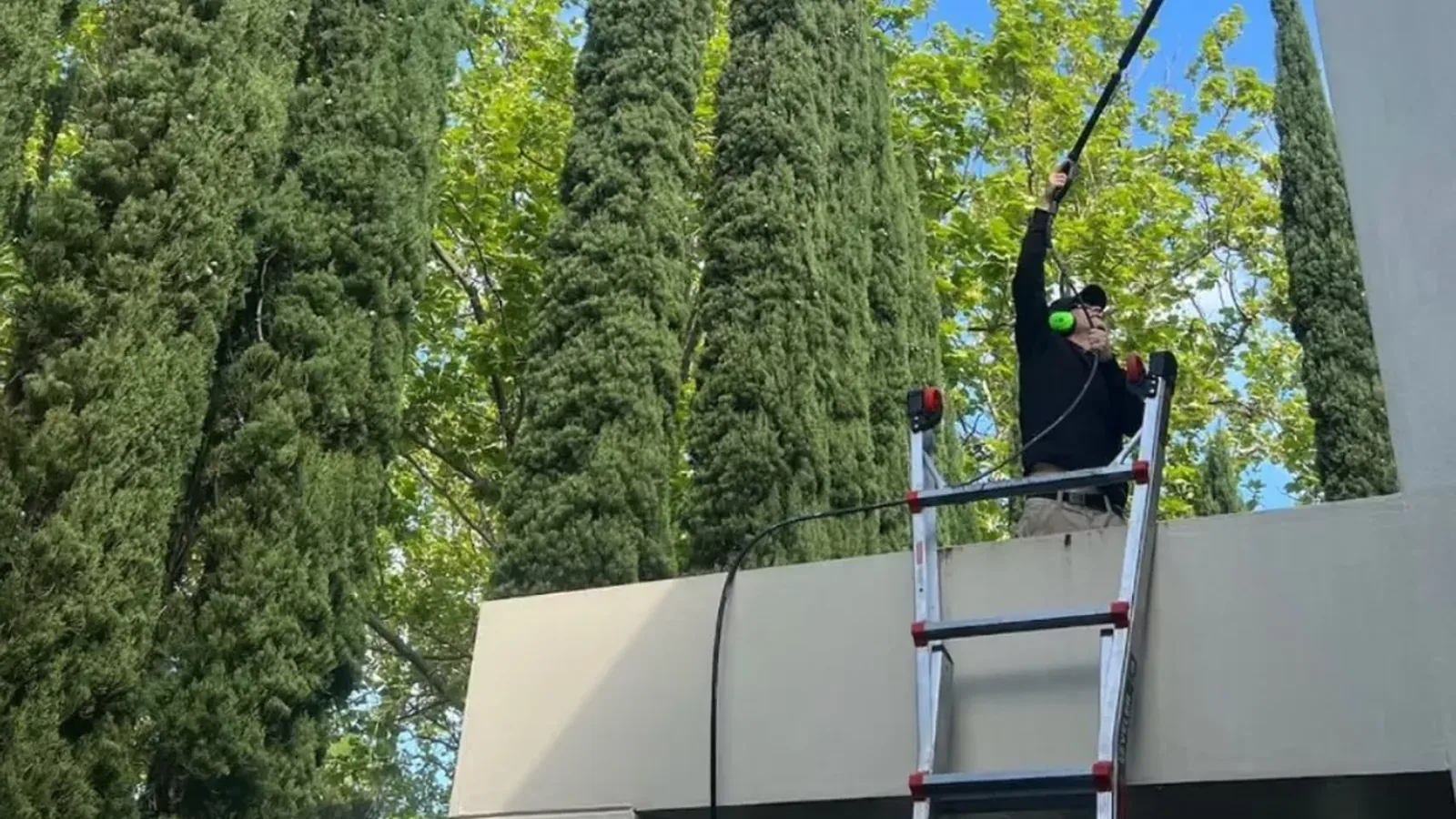 Stan The Man Cleaning using a water-fed pole to clean a glass facade under blue skies in Melbourne's Eastern Suburbs