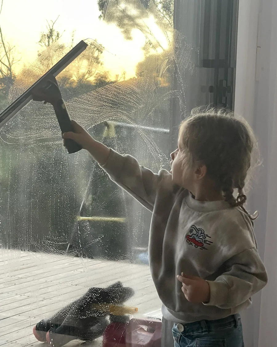 Deanna, the little apprentice at Stan The Man Cleaning, cleaning a window at sunset